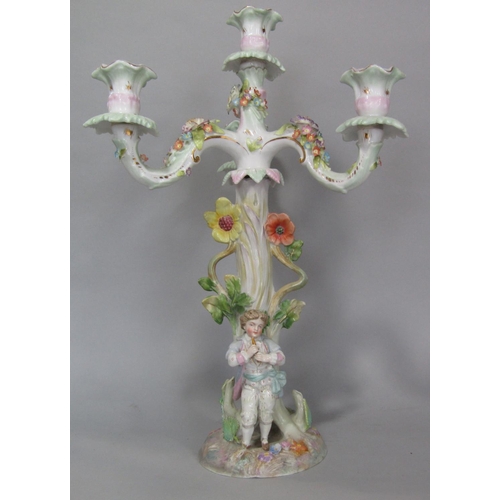 100 - A late 19th century German porcelain three branch candelabra with a piper standing beneath a tree, t... 