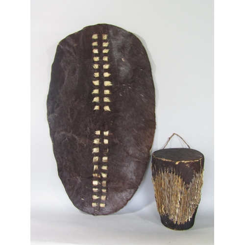 545 - Tribal interest - hide covered drum, 27 cm high, together with a further hide shield 79 cm long (2)