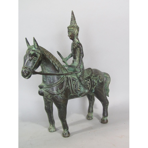 611 - An eastern cast bronze figure of a Buddhistic deity riding a horse, 26cm high, together with a furth... 