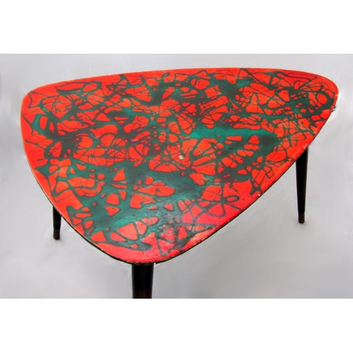 210 - 1950s Italian coffee table the red lacquered top with abstract design upon three ebonised tapered le... 