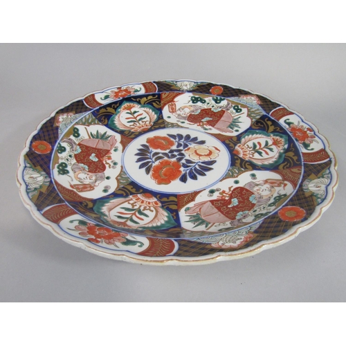 1089 - A 19th century imari type charger with male character and floral decoration, with shaped rim and imp... 