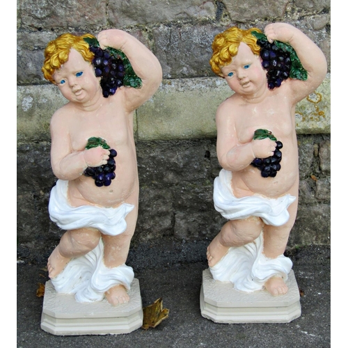 2080 - A matched pair of reclaimed garden ornaments in the form of standing cherubs, holding bunches of gra... 