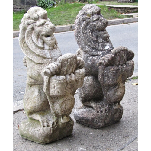 2089 - A pair of reclaimed garden ornaments or pier caps in the form of seated lions clutching armorial shi... 