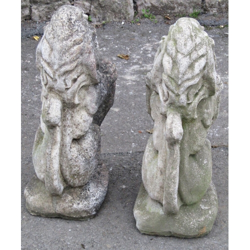 2089 - A pair of reclaimed garden ornaments or pier caps in the form of seated lions clutching armorial shi... 