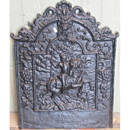 2094 - A cast iron fireback of stepped arched form, with raised relief lions mask, fruiting vine and horsem... 