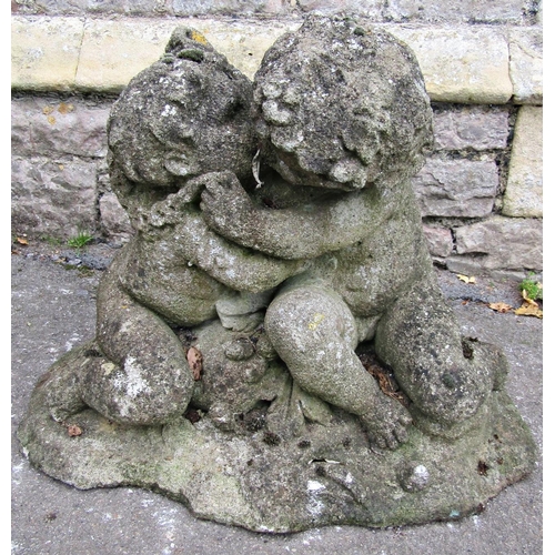 2106 - A well weathered reclaimed garden ornament in the form of embracing kissing cherubs in seated pose r... 