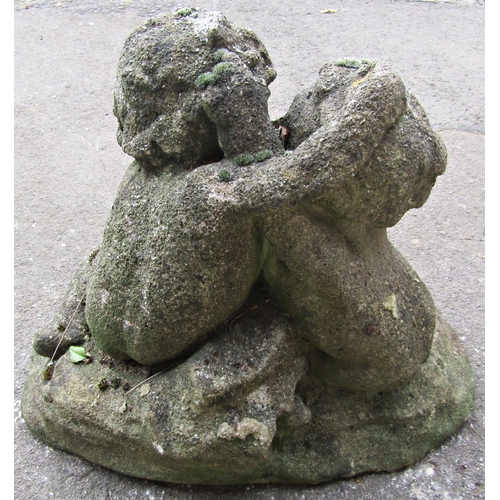 2106 - A well weathered reclaimed garden ornament in the form of embracing kissing cherubs in seated pose r... 