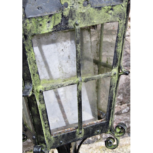 2109 - A pair of iron work lanterns with tapered glazed panels, scrolled detail and supports with square fi... 