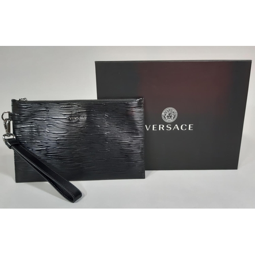 1551 - Black pouch/ bag by Versace with textured surface, wrist strap and zip fastening, boxed