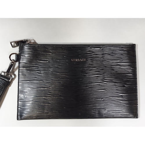 1551 - Black pouch/ bag by Versace with textured surface, wrist strap and zip fastening, boxed