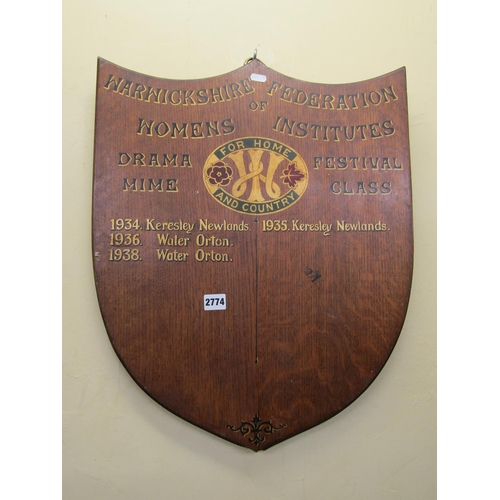 2774 - An oak shield shaped panel, painted detail Warwickshire Federation of Women's Institutes, 60 cm max