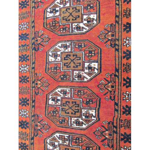 1479 - A middle eastern rug with a central row of four medallions upon a rust red ground, 150 x 100cm