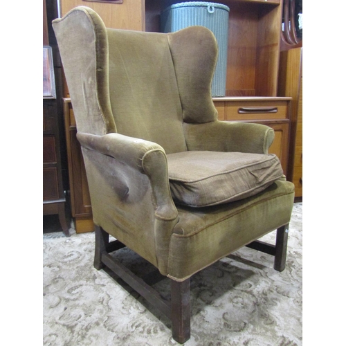 2332 - A Georgian style wing armchair, with shaped and rolled outline and upholstered finish, raised on squ... 