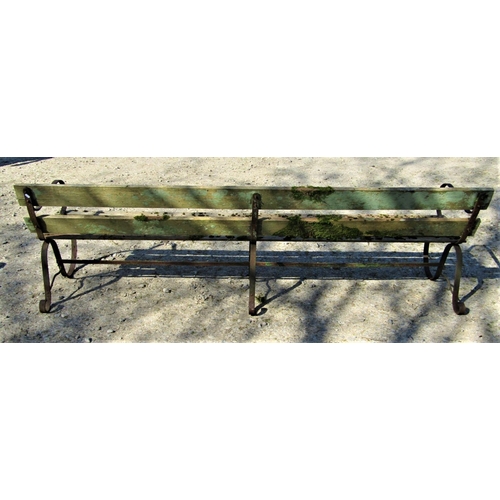 11 - A vintage park or garden bench with weathered timber slatted seat and low back rails, raised on spru... 