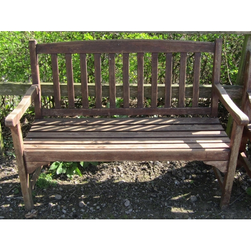 13 - A weathered contemporary two seat garden bench with slatted seat and back, beneath a slightly arched... 