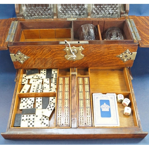 1136 - A Victorian oak games tantalus with brass overlay, having three matching decanters and two glasses, ... 