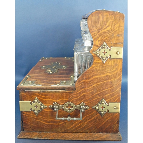 1136 - A Victorian oak games tantalus with brass overlay, having three matching decanters and two glasses, ... 