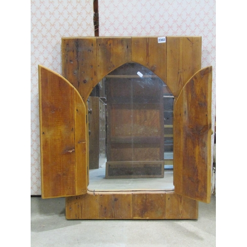 2302 - Stripped and waxed pine framed mirror enclosed by two hinged arched doors, 80 x 58cm