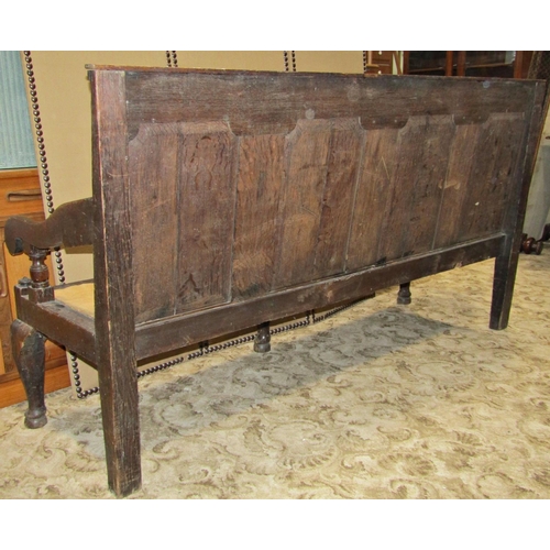 2351 - A Georgian oak settle, the raised panelled back crossbanded in walnut, with scrolled arms on shaped ... 