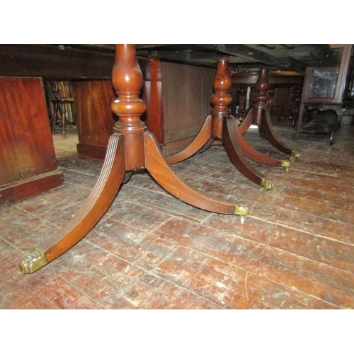 2414 - A Georgian style mahogany three pedestal dining table on turned columns and reeded sabre supports, t... 