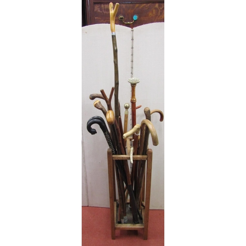 2443 - An oak four divisional stickstand enclosing a mixed arrangement of walking sticks, riding crops, etc