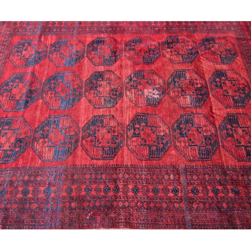 2462 - A large Afghan designed carpet with a central panel of elephant feet on a red ground. 310cm x 230cm ... 