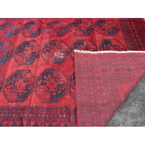 2462 - A large Afghan designed carpet with a central panel of elephant feet on a red ground. 310cm x 230cm ... 