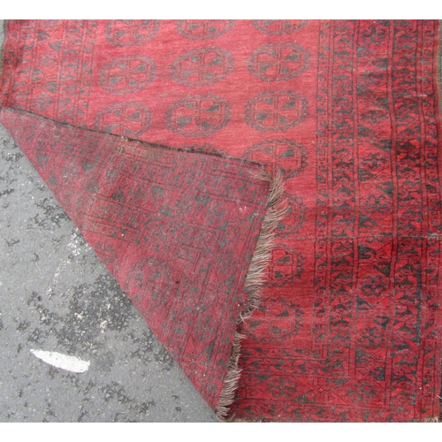 2468 - A Turkoman carpet with three rows of medallions on a red ground. 180cm x 125cm