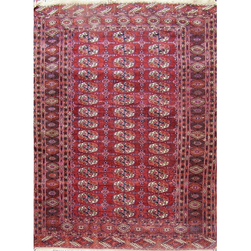 2489 - A Tekke carpet with a field of three rows of gul with highlights of purple on a faded red ground. 20... 