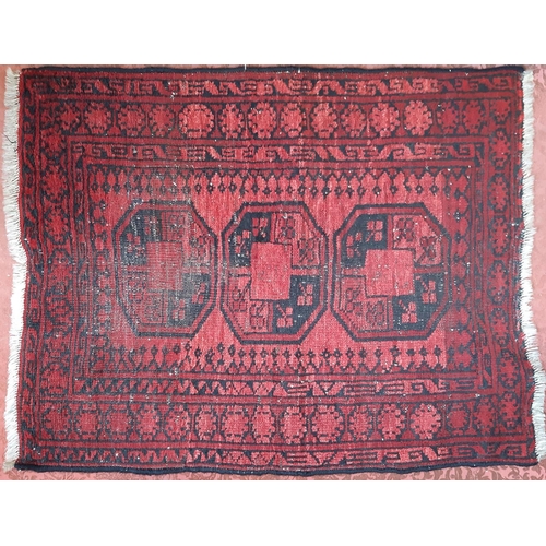 2527 - A small Turkamen rug with three medallions on a red ground. 110cm x 85cm