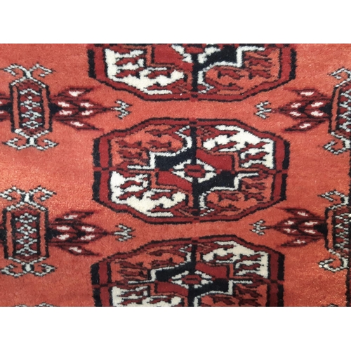 2528 - A Turkoman carpet with three rows of elephant foot gul on a faded red ground. 180cm x 124cm approx