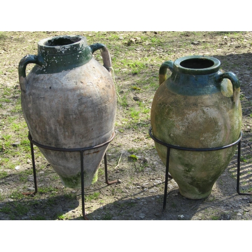 2028 - A weathered terracotta Turkish amphora with moulded loop handles, green glazed neck and set in a sim... 