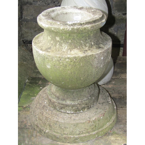 1071 - A small weathered marble urn raised on an associated stepped circular composite base together with a... 