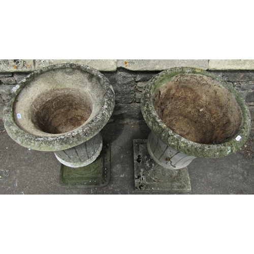 1085 - Two similar weathered cast composition stone garden urns of circular tapered form with flared repeat... 