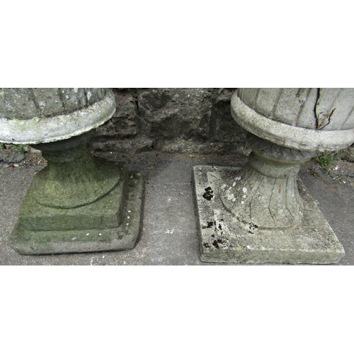 1085 - Two similar weathered cast composition stone garden urns of circular tapered form with flared repeat... 