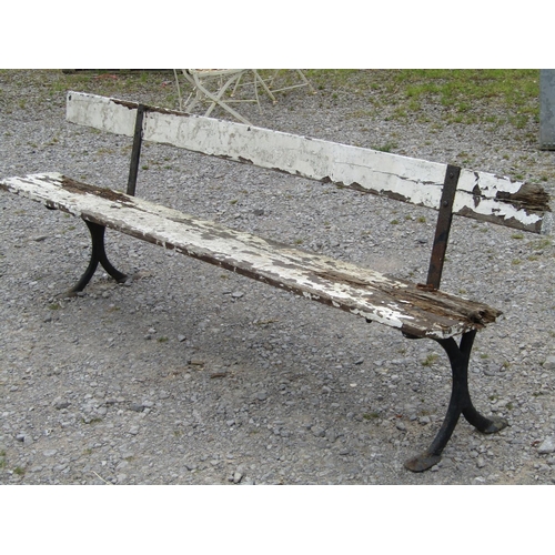 1018 - An old platform bench with painted and weathered wooden plank seat and back rail, raised on cast iro... 