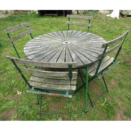 1061 - A weathered circular garden table with hardwood sunburst patterned top raised on green painted tubul... 