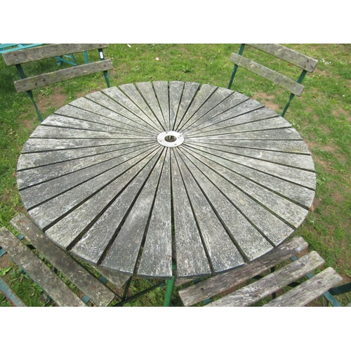 1061 - A weathered circular garden table with hardwood sunburst patterned top raised on green painted tubul... 