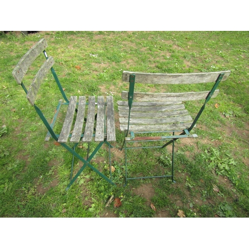 1061 - A weathered circular garden table with hardwood sunburst patterned top raised on green painted tubul... 