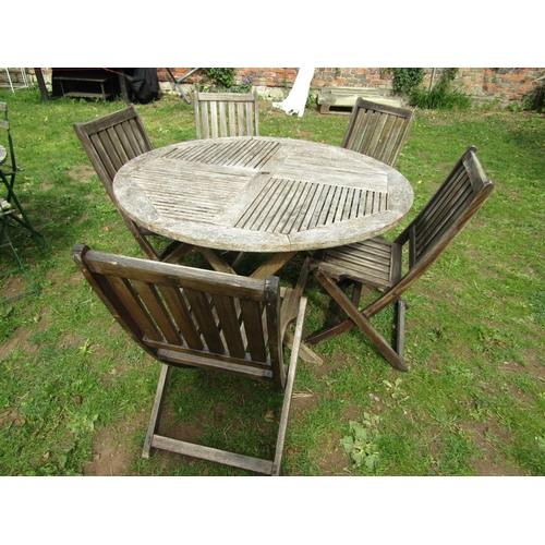 1064 - A weathered hardwood circular topped garden table with slatted panels raised on x framed folding sup... 