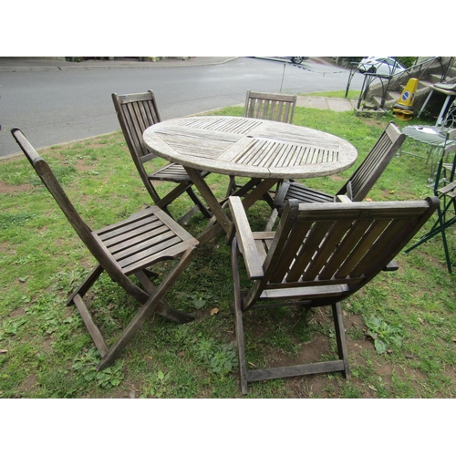 1064 - A weathered hardwood circular topped garden table with slatted panels raised on x framed folding sup... 