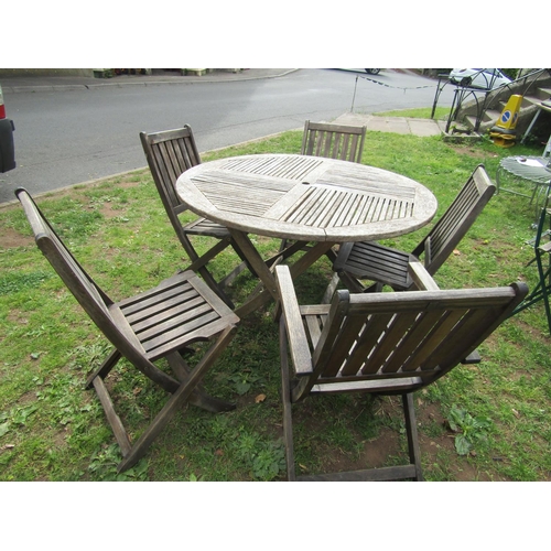 1064 - A weathered hardwood circular topped garden table with slatted panels raised on x framed folding sup... 