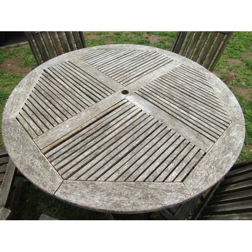 1064 - A weathered hardwood circular topped garden table with slatted panels raised on x framed folding sup... 