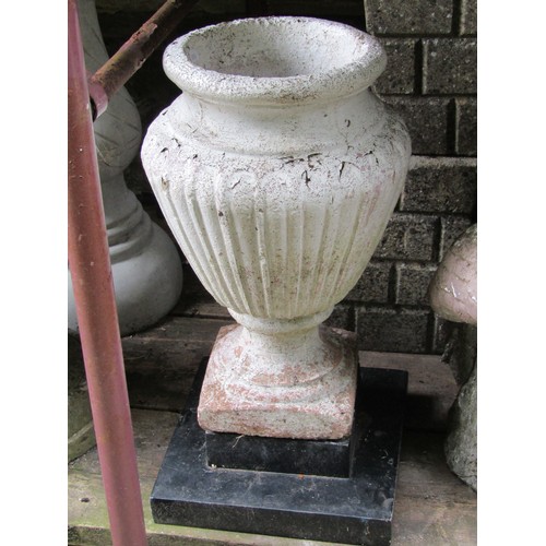 1071 - A small weathered marble urn raised on an associated stepped circular composite base together with a... 