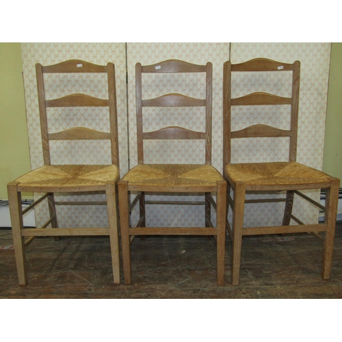 1671 - A Harlequin set of three pale oak ladderback chairs, almost certainly Heals, with rush seats n squar... 