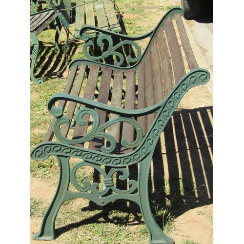 1084 - A two seat garden bench with weathered hardwood lathes, raised on green painted decorative cast iron... 