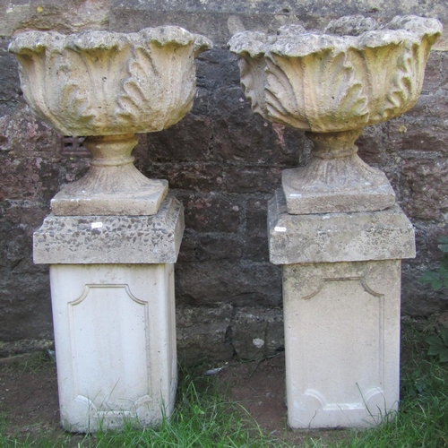 1069 - A pair of weathered cast composition stone garden urns, with circular acanthus leaf bowls raised on ... 