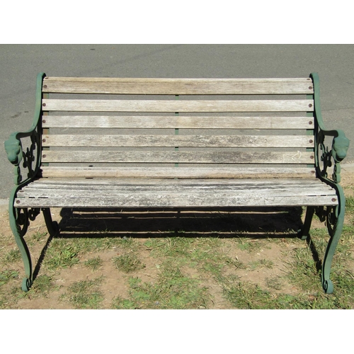 1085 - A two seat garden bench with weathered timber lathes, raised on green painted decorative cast iron e... 