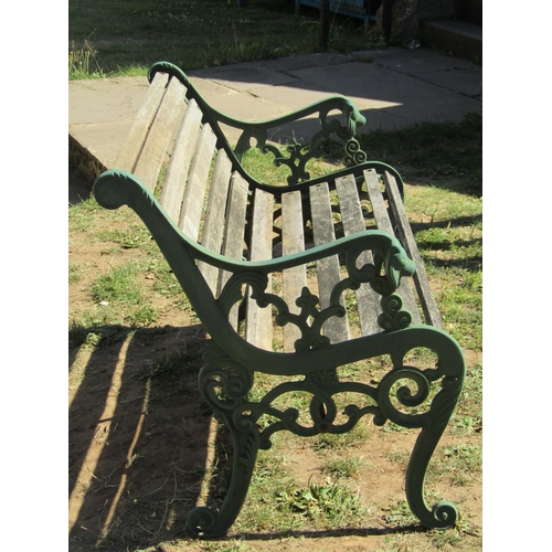 1085 - A two seat garden bench with weathered timber lathes, raised on green painted decorative cast iron e... 