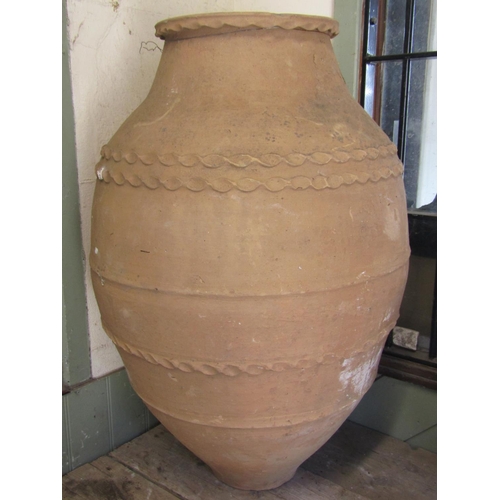 1113 - A weathered terracotta oviform olive jar with simple thumb pressed bands and ribbed detail, 84 cm hi... 